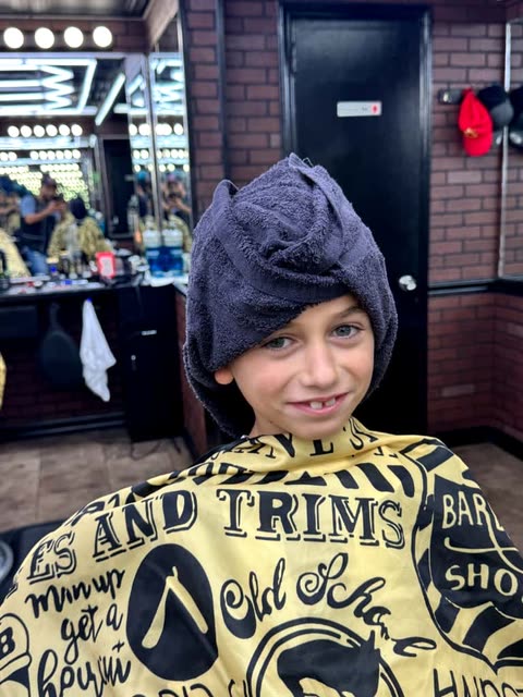 A child with a towel round his shoulders after a cut