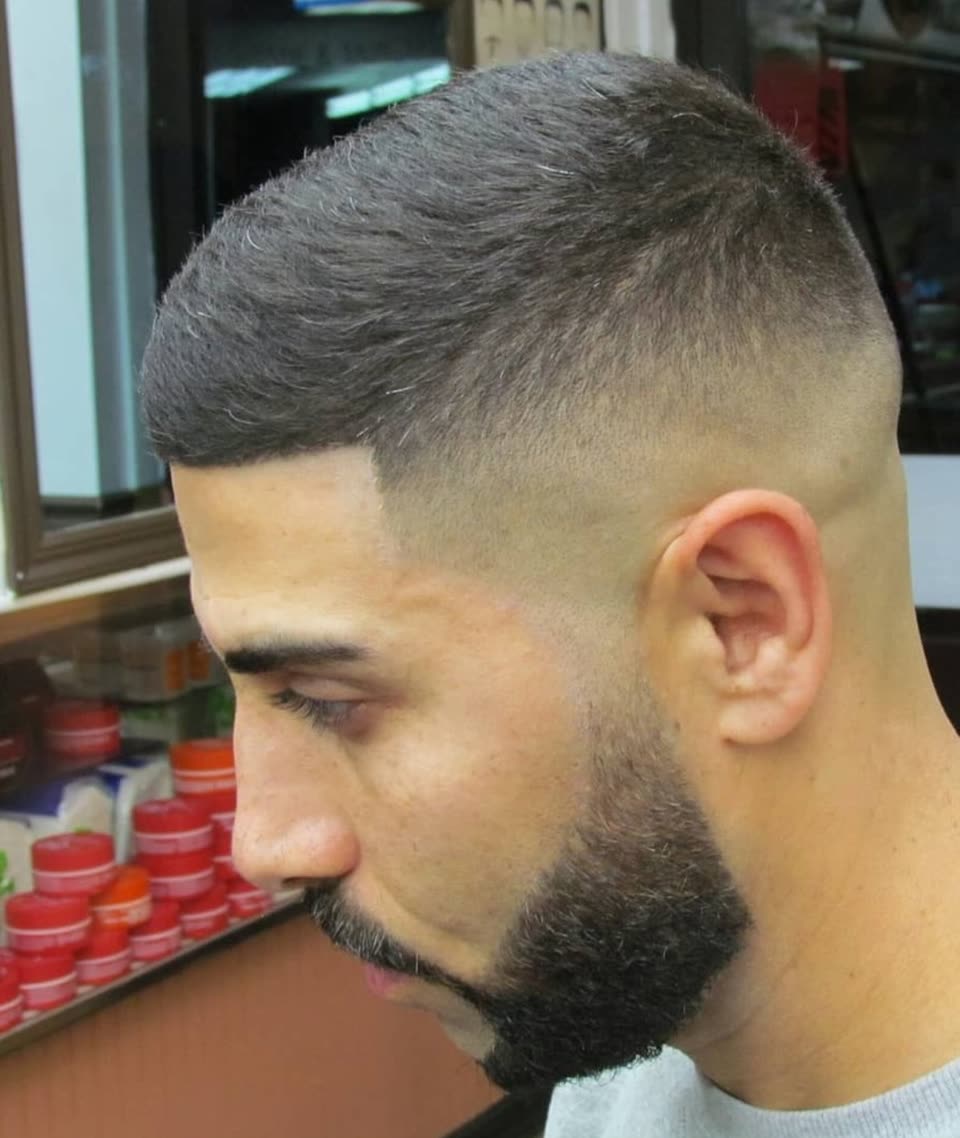 A skin fade in side profile against the brick wall outside the shop
